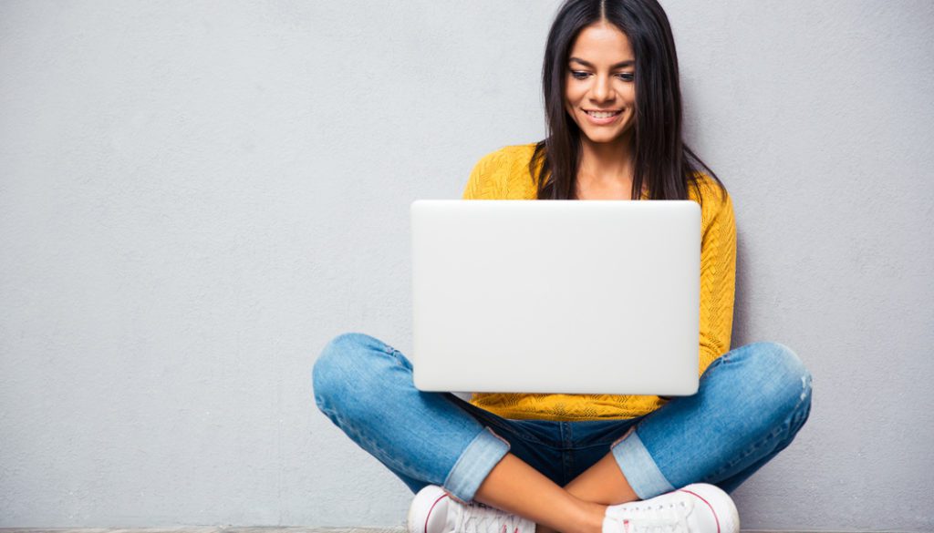 young girl sitting on the floor using a laptop computer